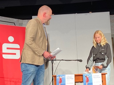 Moderator Jan Graf überlässt Maite Rudolph die Bühne für ihren Lesevortrag