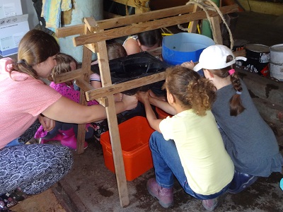 Kinder üben das Melken an einer Euteratrappe.